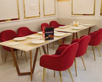 a table with a table setting with red chairs and gold accents