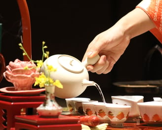 une personne verse de l'eau dans des tasses lors d'une cérémonie du thé