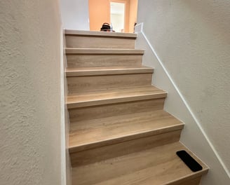 Modern staircase renovation with hardwood treads, black metal railings, and open risers in a Kissimm