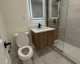 Custom bathroom remodel featuring frameless glass shower, dual sinks, and LED mirror lighting in a C