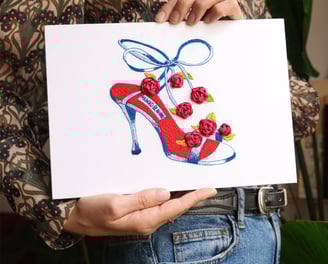a woman holding a card with a drawing of a shoe