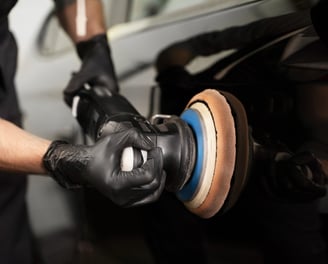 Polissage d'une carrosserie de véhicule noir avec une polisseuse orbitale