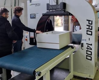 a man standing in front of a machine that is cutting into a piece of paper