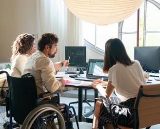 Equipe diversa em reunião estratégica, incluindo profissional cadeirante com produtividade