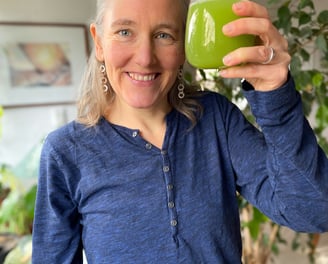 Selleriesaft wird im Glas in einer fröhlichen Geste hochgehalten