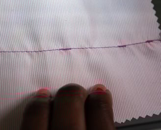 Backstitching shown on pink fabric