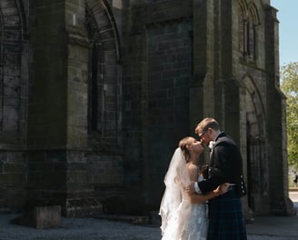 a bride and groom kissing in front of a church