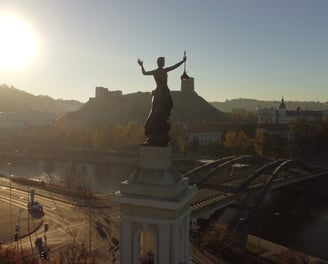 Saulė šviečia į energetikos muziejų Vilniuje, Gedimino pilis tolumoje, drono fotografija