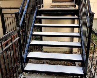 A sturdy metal staircase with concrete steps, built for durability and style. The strong steel frame