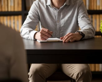 a man and woman sitting at a table with a notebook and pen