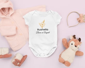 Flat lay of a personalised white baby grow with a red rose and 'Born in June' text, surrounded by so