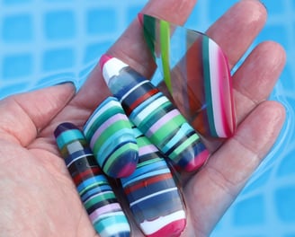 a hand holding a selection of surfite or surf stone cabochons in bright colours