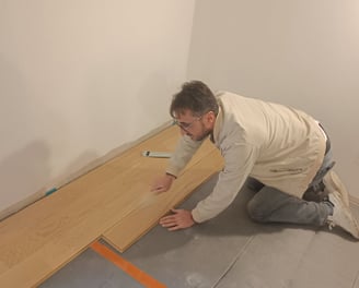 Un artisan qui pose du parquet flottant en bois.