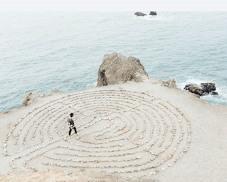 Une personne marche sur un labyrinthe façonné sur une plage