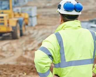 a construction worker in a yellow safety vest and safety glasses