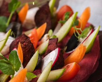 Ensalada colorida con hummus de remolacha, crudités frescos y falafel, servida en un bol artesanal.