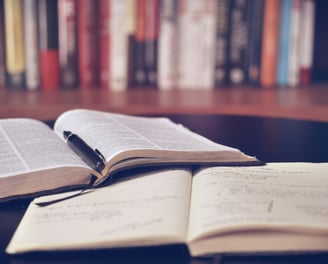 Book open with pen on top of notebook with writing