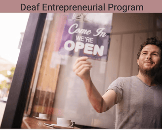 Man turning around Come In We're Open sign on coffee shop window