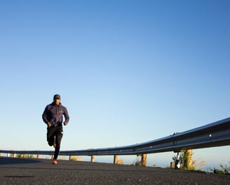 un homme court sur la route près d'une barrière de sécurité
