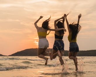 three women jumping in the air in the ocean