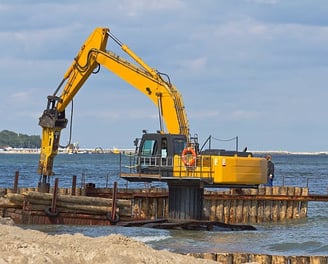 excavator holding logs for dock construction