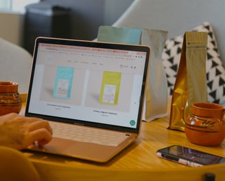 a person sitting at a table with a laptop and a cup of coffee