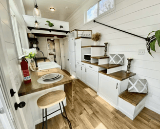 Cozy kitchen and stairs inside modern tiny home on wheels