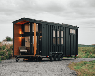 Sleek black modern tiny home on wheels with porch seating