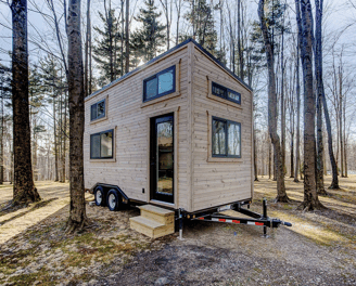 Compact wooden tiny home on wheels parked in the forest