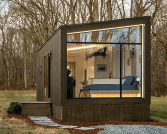 Modern tiny home on wheels with large glass windows in nature