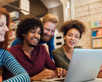 a group of people sitting around a laptop computer