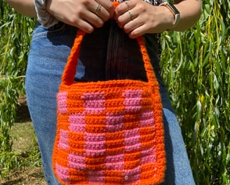 Handmade crochet shoulder bag in a green and pink checkerboard pattern