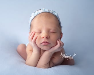 Una niña recién nacida durmiendo con las manos sobre la cabeza.