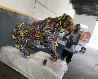 érgio Astral posando ao lado de sua criação, uma escultura de onça-pintada estilizada