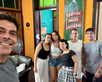 Group of people in a language school in Rosario, with a sign that reads ‘SPANISH INGLES in ROSARIO’