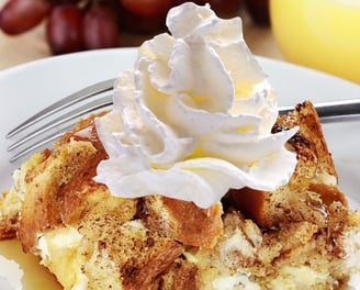 a piece of bread pudding with whipped cream on top of it