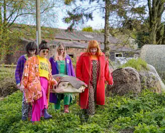 four young women carrying a body wrap in a shroud on a bowsprit and standing rigging