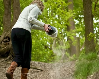 a women scattering ashes in woodlands