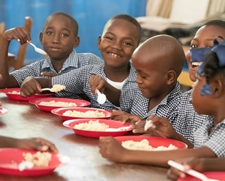 Young kids enjoy a school program offering meals to students for lunch