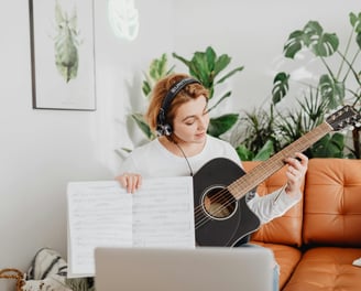 Online guitar lesson displayed on a computer screen with a virtual instructor