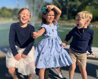 three children playing with a fountain in a park