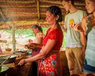 a woman cooking food in a hut with a man and a woman