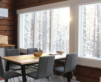 dining room table in log house with large panoramic windows and views of snowy forrest
