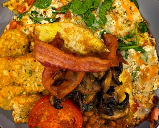 a plate of food with eggs, hashbrowns, bacon, beans, mushrooms