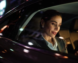 Empresária usa o celular enquanto está em um carro de transferência em uma rua urbana com letreiros