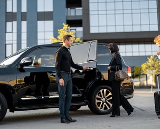 O motorista ajuda um casal de empresários a entrar no carro, abrindo a porta de um táxi preto de lux