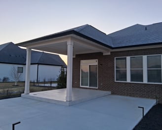Covered patio with raised concrete floor under a roof with a larger uncovered concrete slab patio.