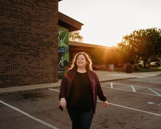 Confident woman walking with community center in background