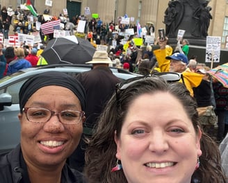 Two women standing in front of large protest group