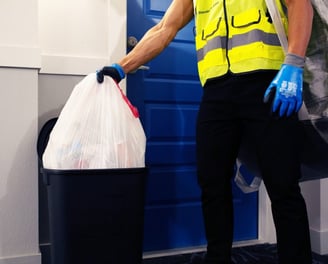 A man picking up trash from a resident's doorstep during valet trash services.